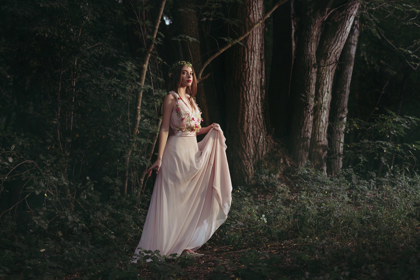 attractive mystic elf in elegant flower dress walking in woods